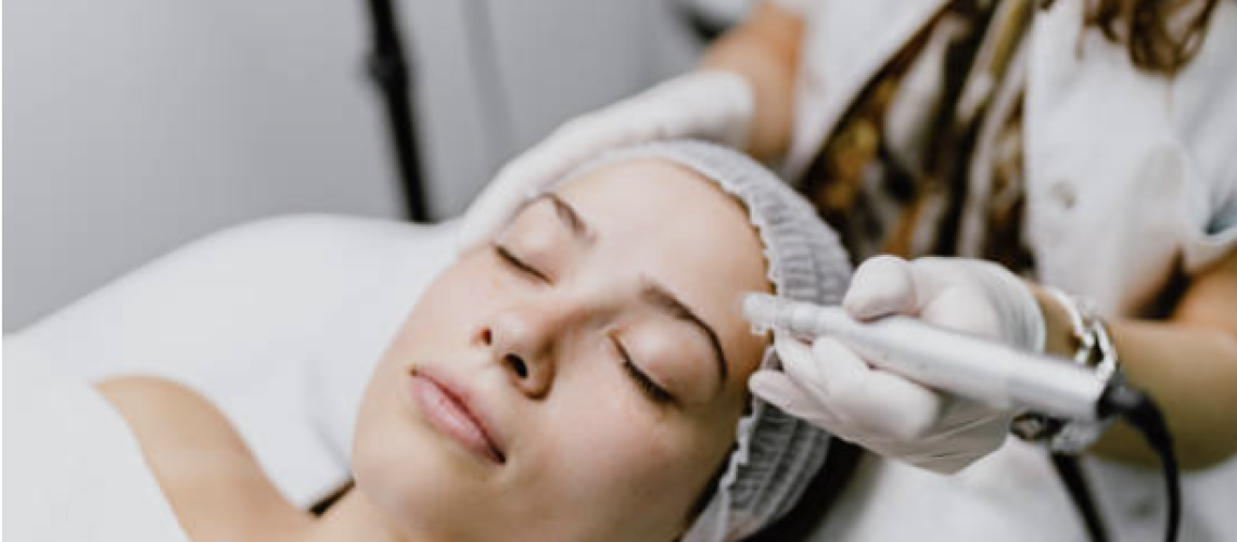 Woman laying down with eyes closed receiving a microneedling skincare treatment from a skincare professional